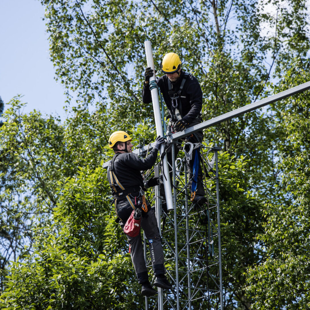 To ansatte øver på å klatre i mast og ta med utstyr.