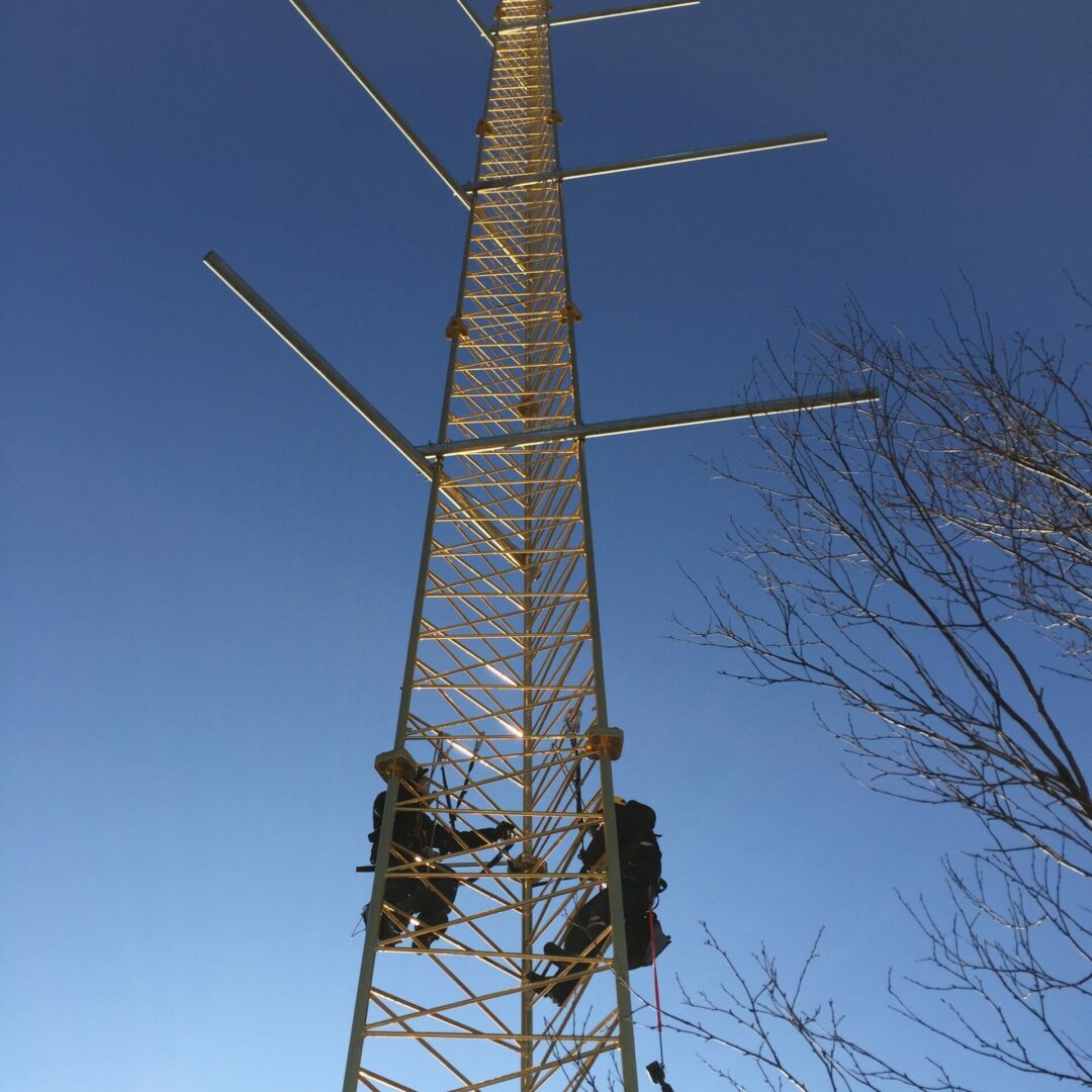 To ansatte klatrer opp i mast for montering av utstyr