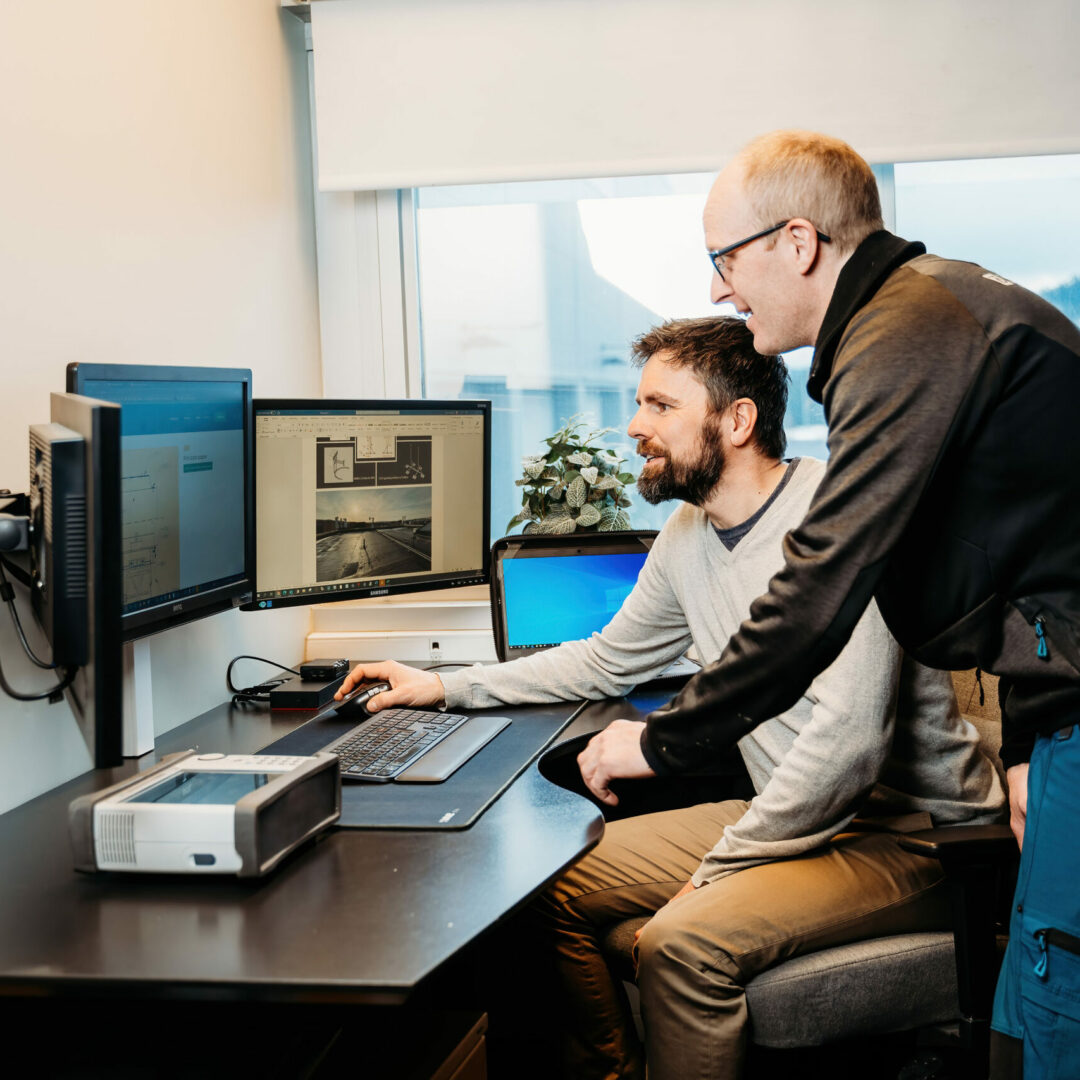 To ansatte samarbeider foran en PC-skjerm